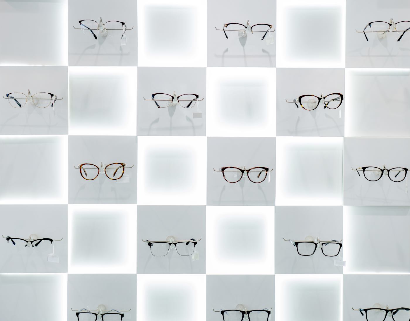Optical eyeglass frames displayed on an illuminated white wall grid