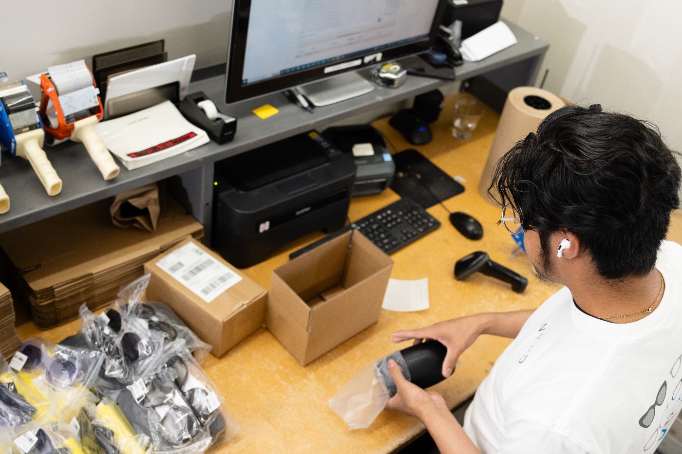 NYWD warehouse associate packing a single order of sunglasses into a shipping box at a fulfillment station
