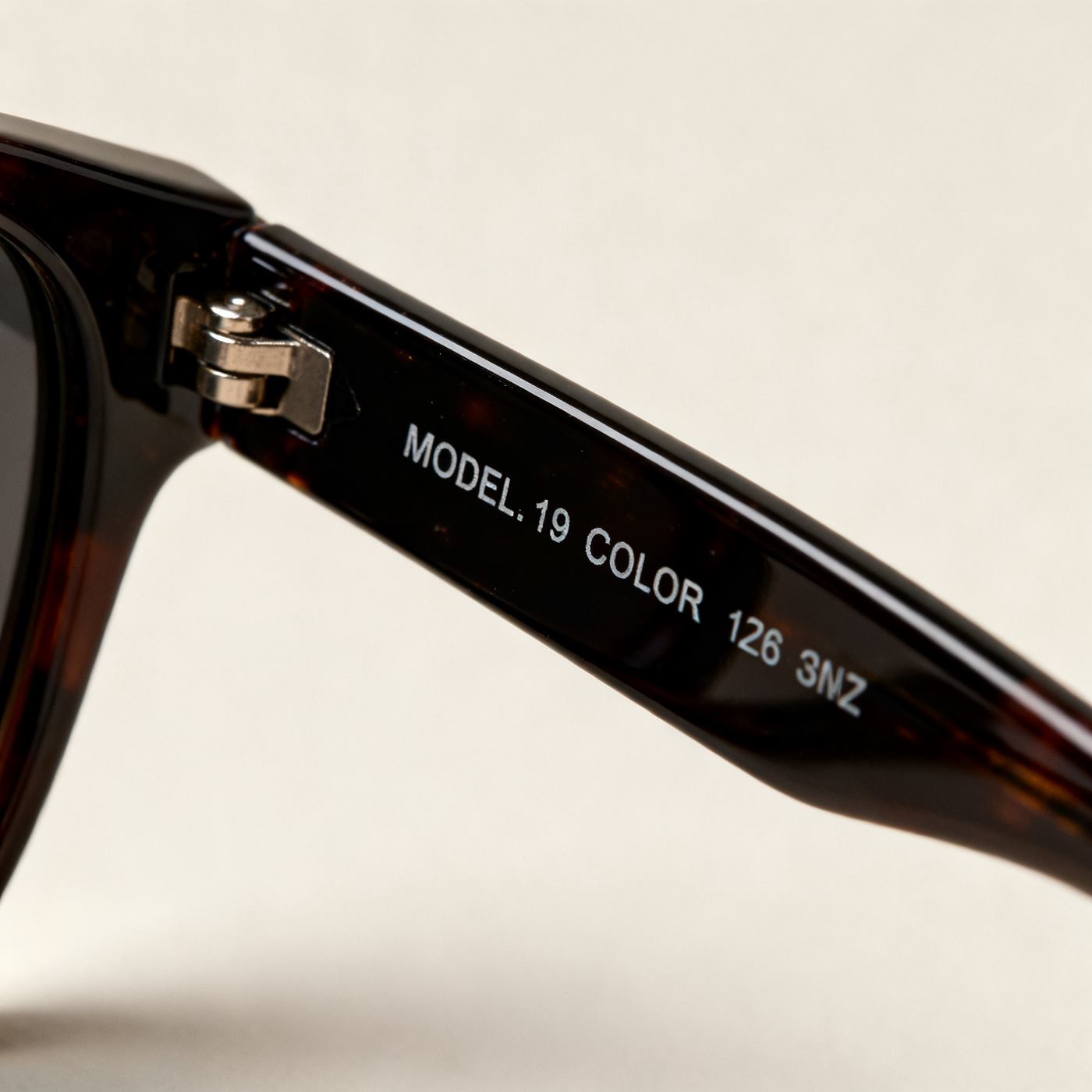 Close-up of the inside of a sunglasses temple arm showing model number, color code and size markings